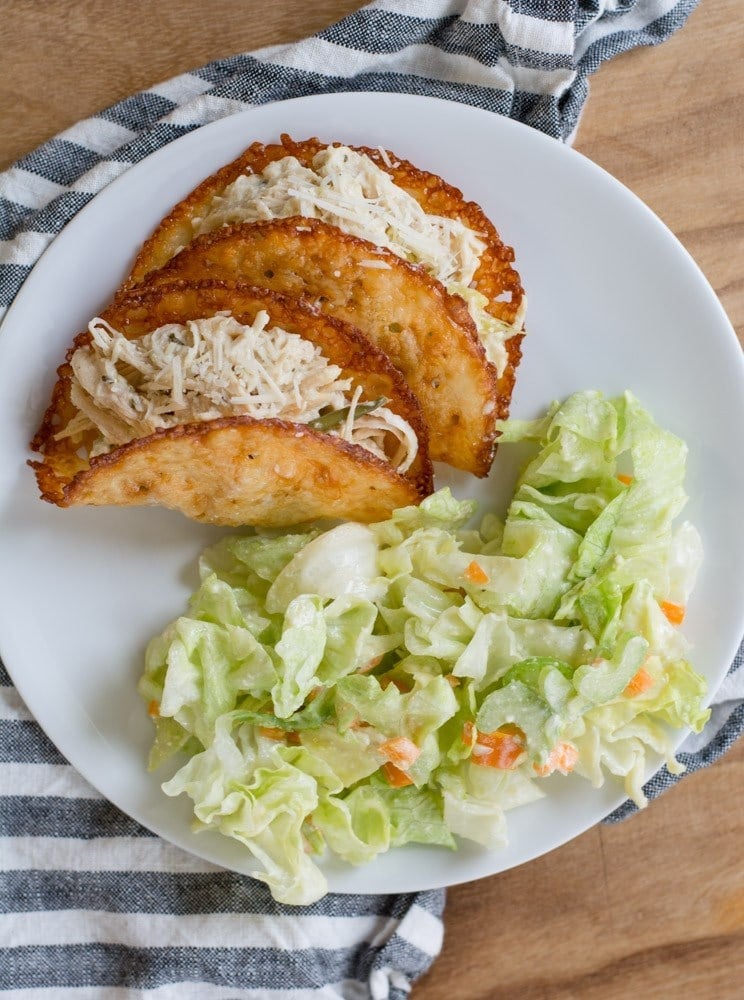 Overhead view of two slow cooker chicken tacos on a plate with a salad