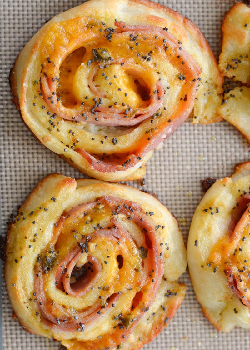 Overhead view of baked keto ham and cheese pinwheels on a silicone-lined tray. 