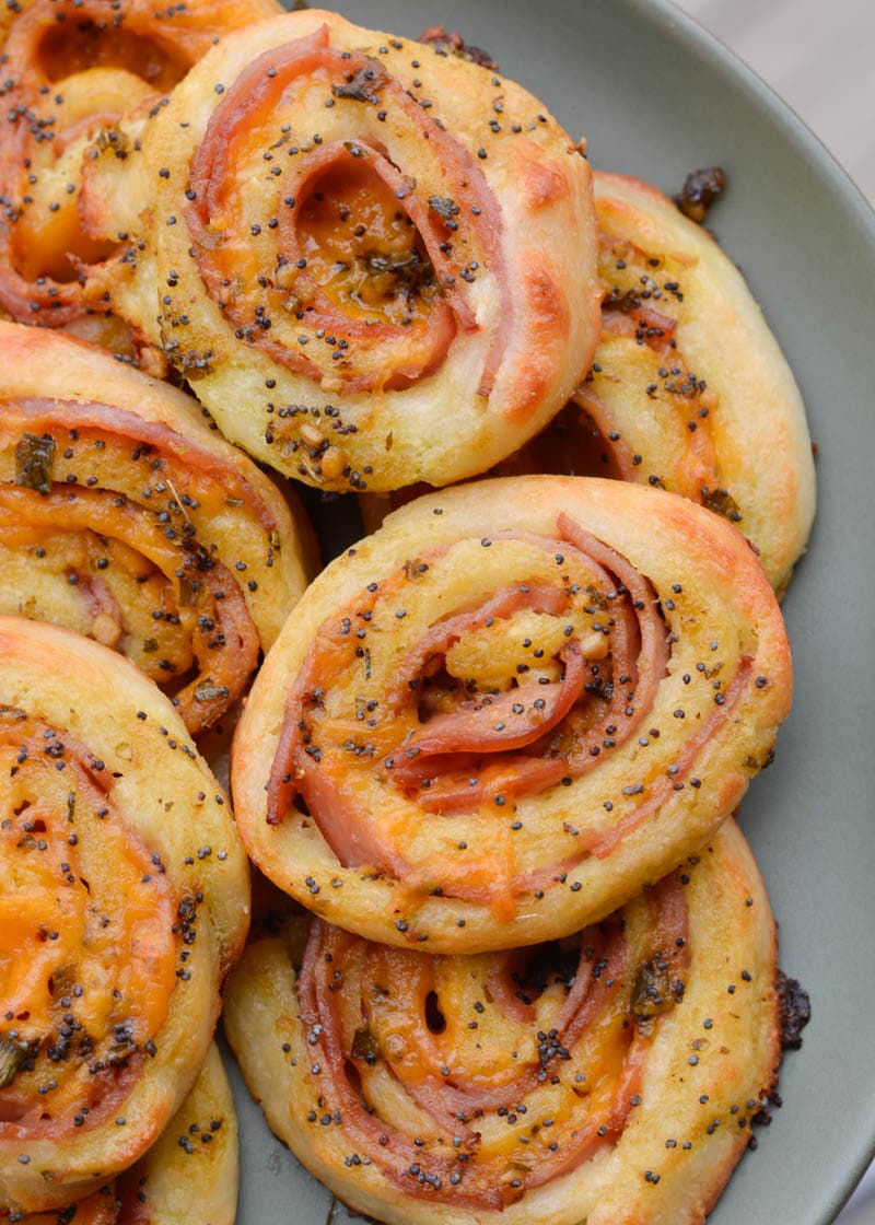 A pile of keto ham and cheese pinwheels on a green plate. 