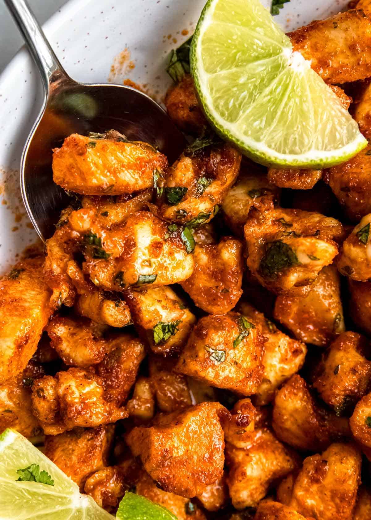 air fryer cilantro chicken bites on a white table with a lime and spoon