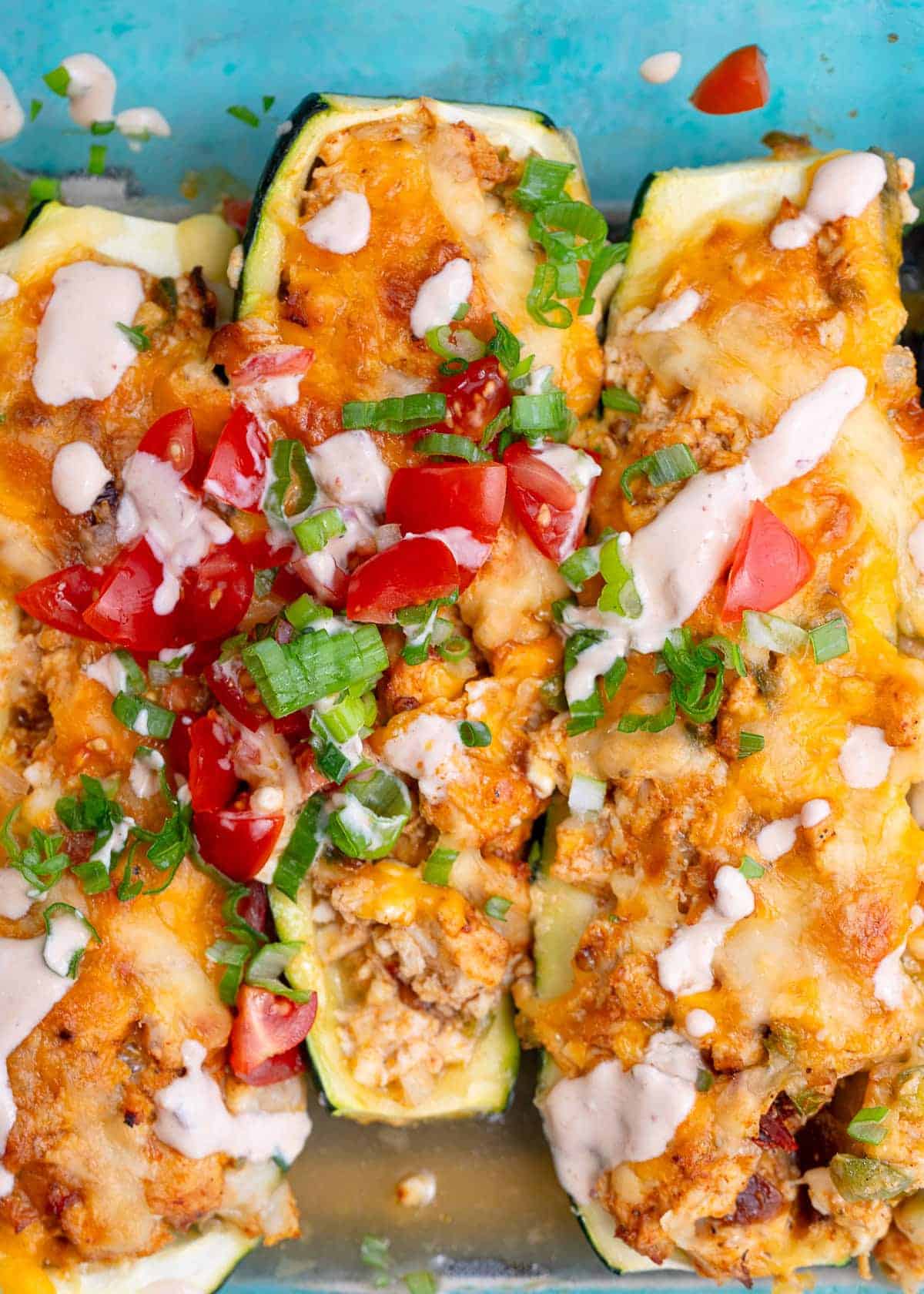 three chipotle chicken zucchini boats on a light blue plate