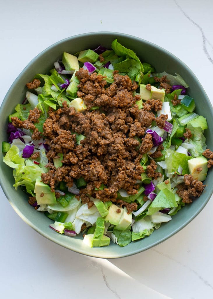 This easy Keto Taco Salad is easy, delicious, and healthy! Top your favorite greens with seasoned meat, tomato, avocado, peppers, and more for a lunch or dinner full of flavor and about 7 net carbs.