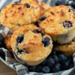 a bowl full of blueberry muffins with fresh berries on the side.