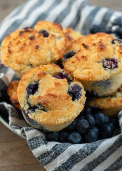 a bowl full of blueberry muffins with fresh berries on the side.