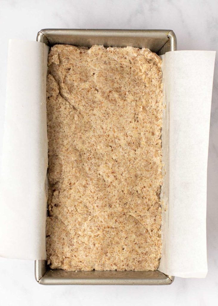 Uncooked bread dough in a loaf pan with parchment paper