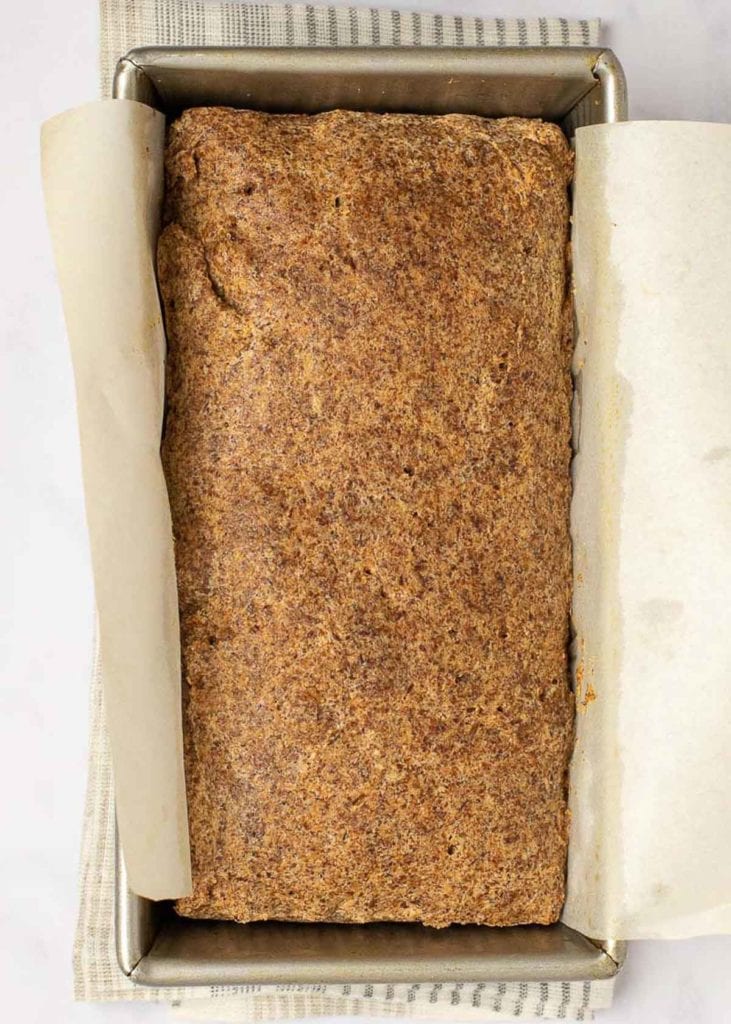 Baked bread in a loaf pan with parchment paper