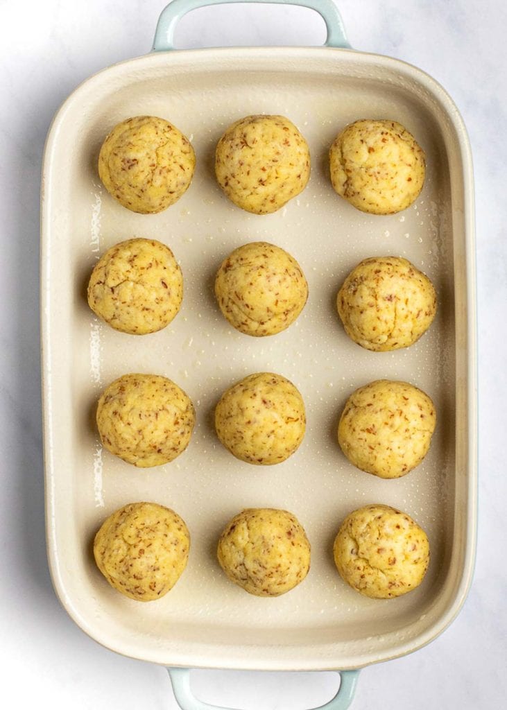 Overhead view of a baking dish with 12 dinner roll dough balls