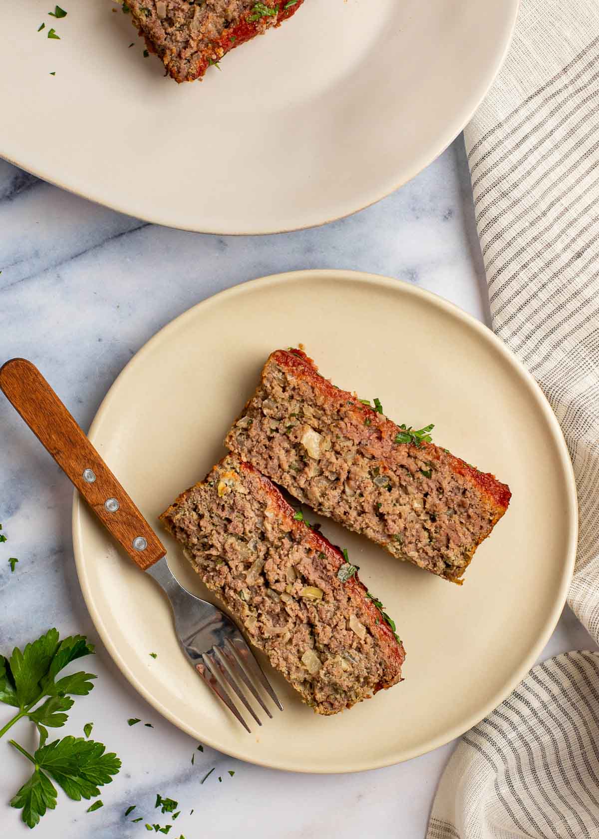 Overhead view of two pieces of meatloaf on a plate with a fork