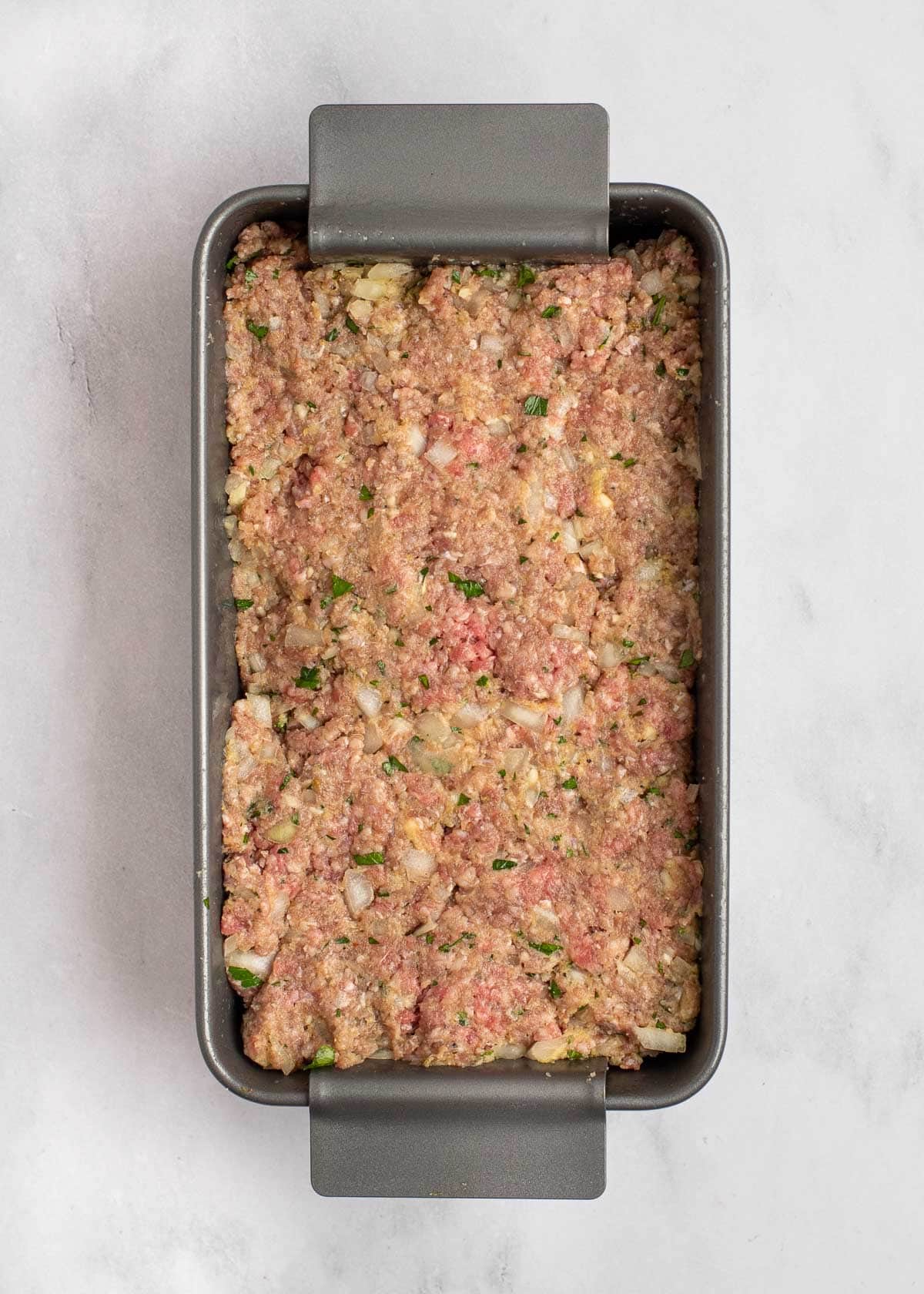 Overhead view of uncooked meatloaf in a loaf pan