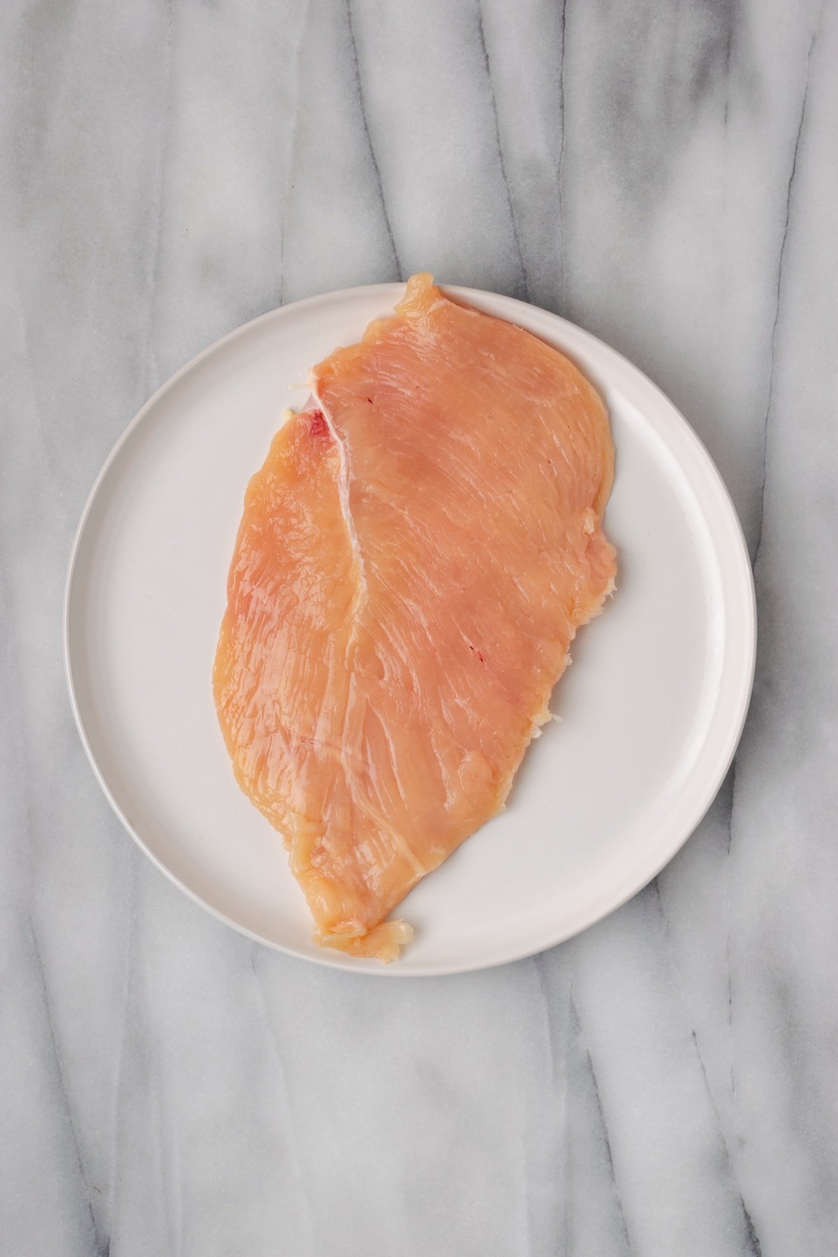 A raw chicken breast on a plate
