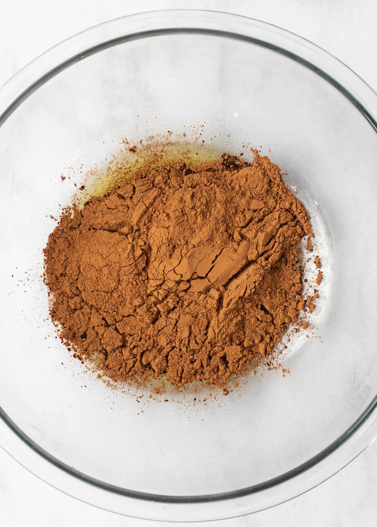 Overhead view of cocoa powder in a mixing bowl on top of melted butter