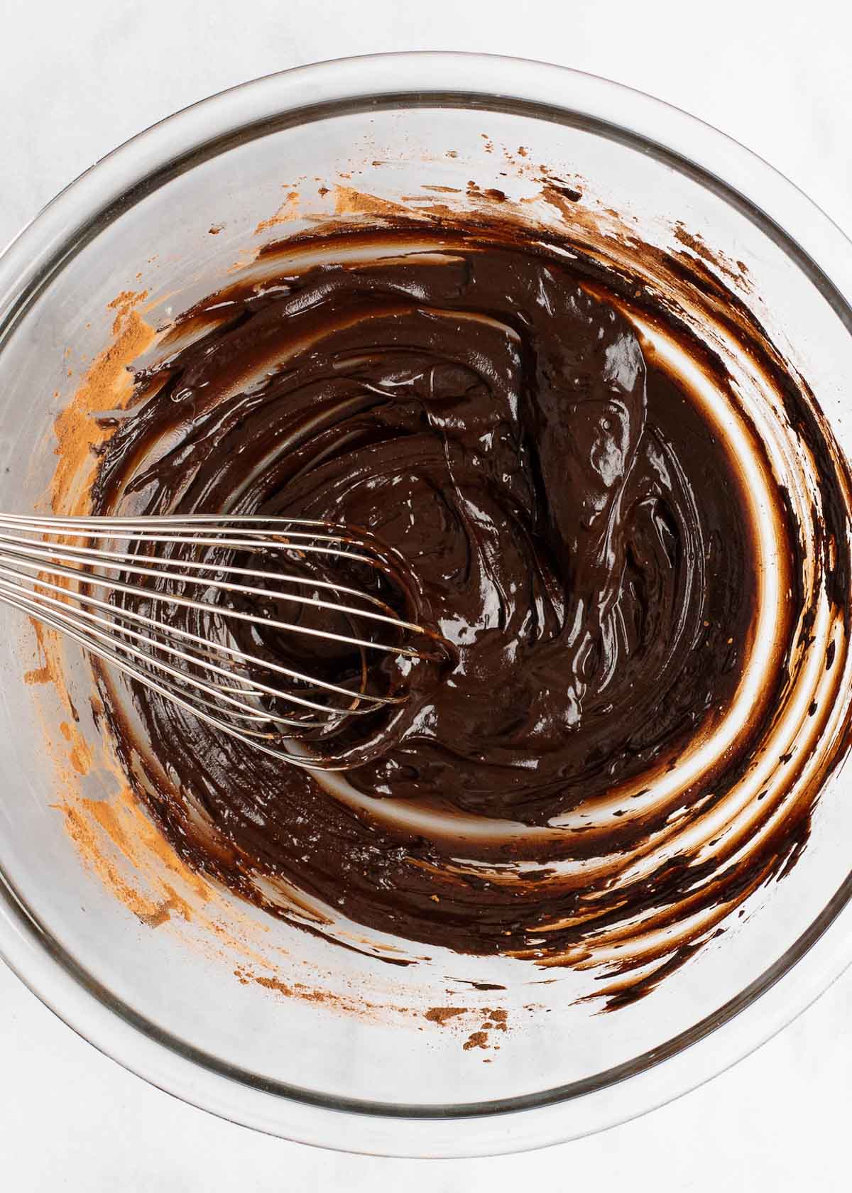 Brownie batter being whisked in clear mixing bowl