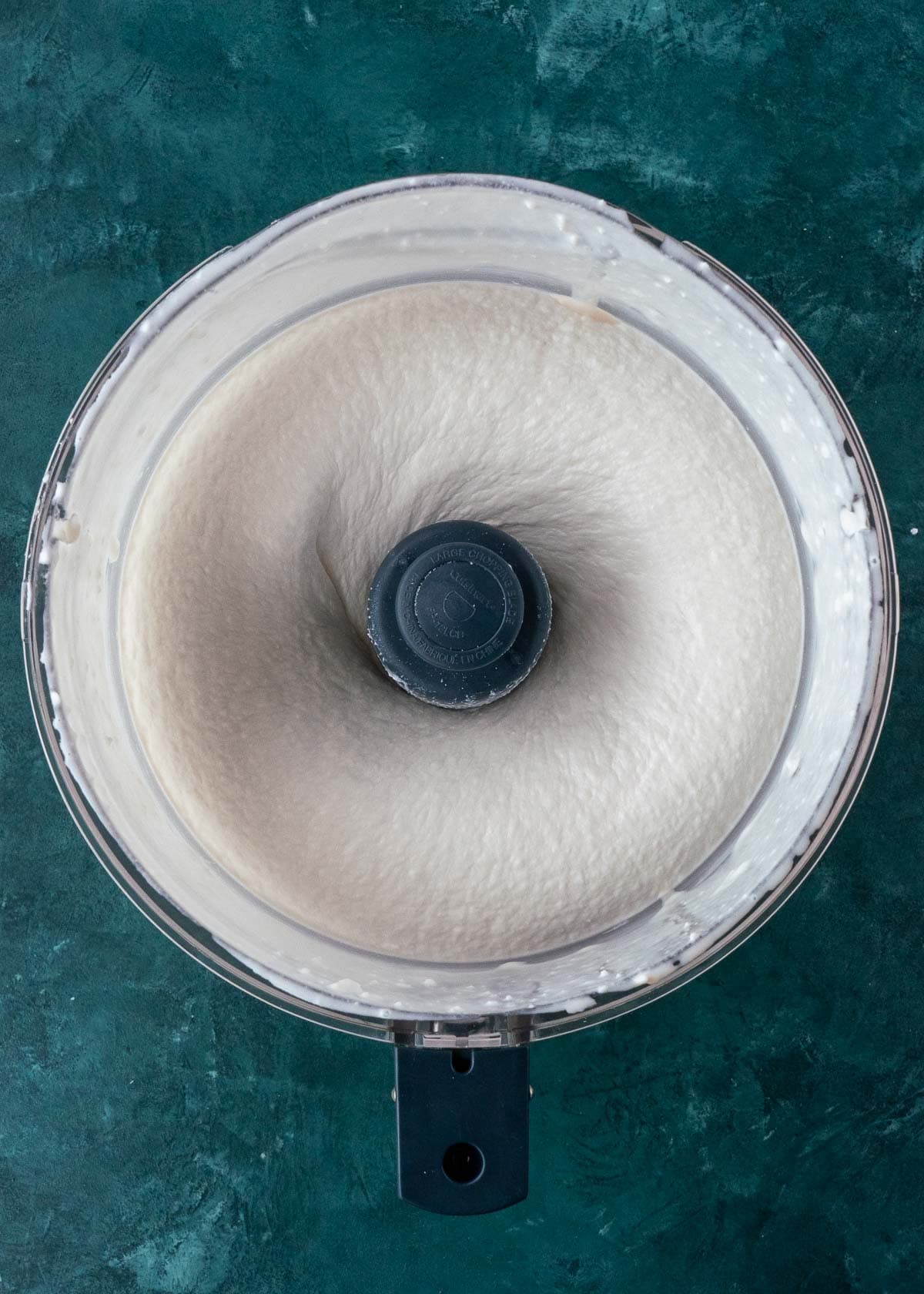 Overhead view of a smooth, blended ice cream base being pulsed in a food processor