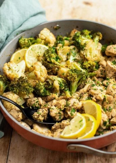 lemon chicken and broccoli with cauliflower in a pan with a spoon