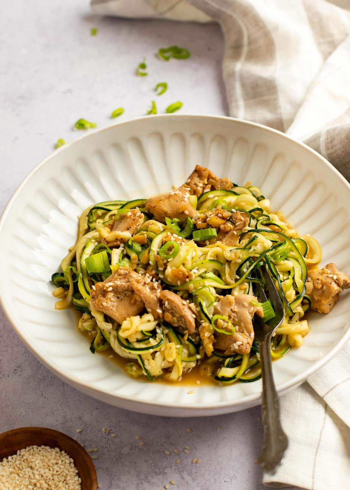 zoodles and sesame chicken on a plate with a fork. 
