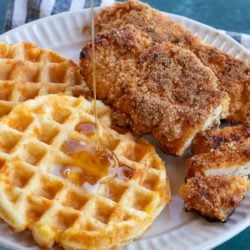 shot of sugar free maple syrup being poured on waffles with crispy chicken tenders
