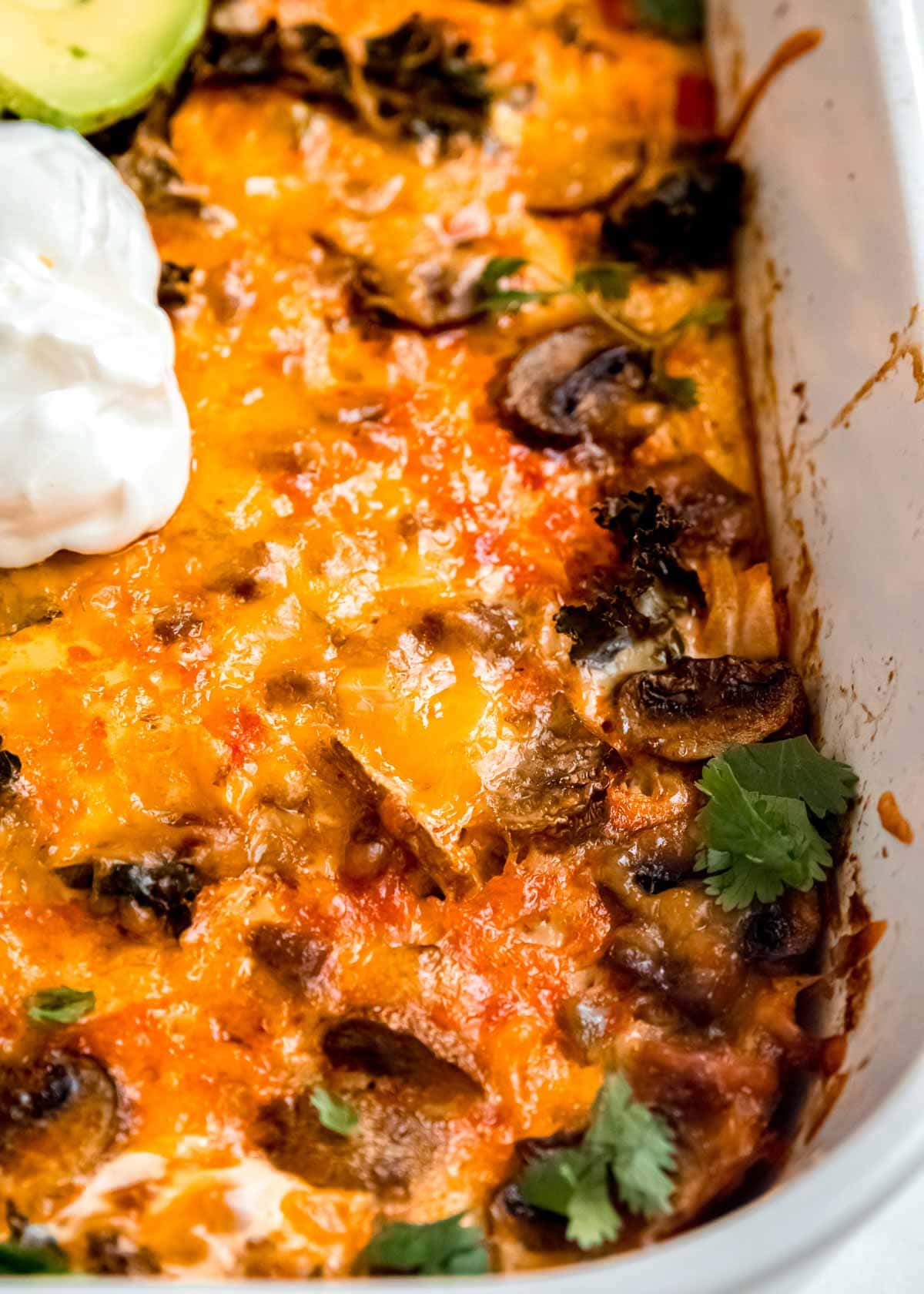 overhead, closeup shot of cooked breakfast casserole garnished with avocado and sour cream