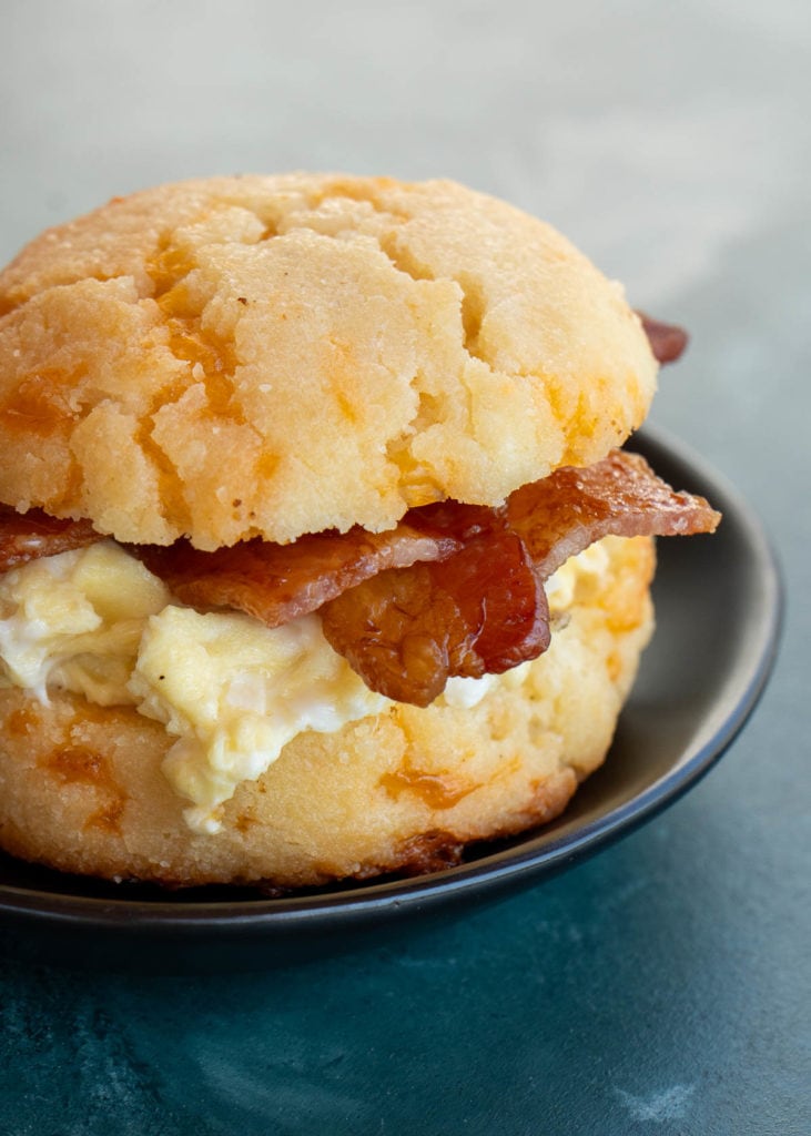 a keto biscuit filled with bacon, eggs and cheese on a black plate