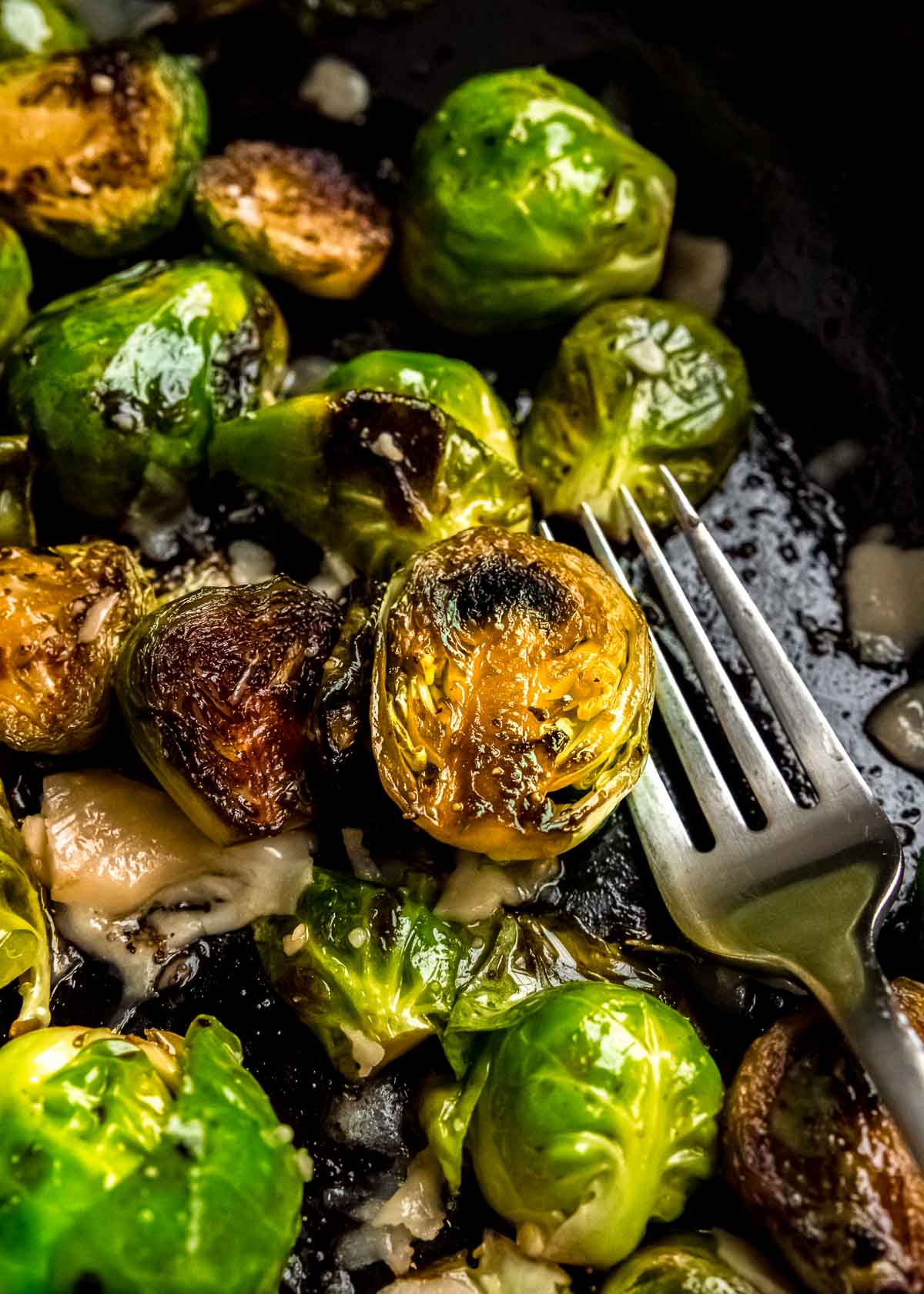 a fork picking up a balsamic brussel sprouts in a pan