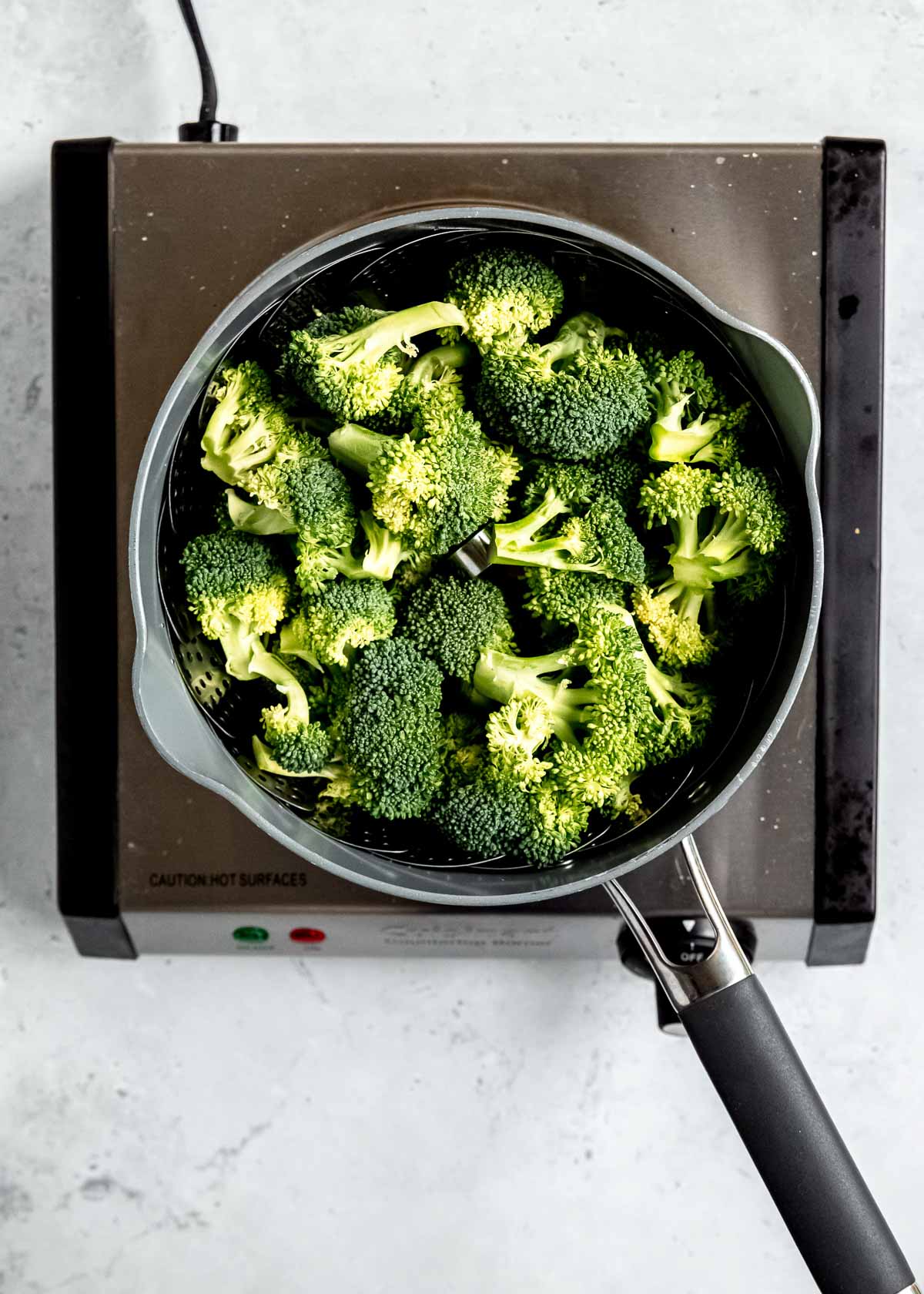 fresh broccoli in a steamer basket in a pot