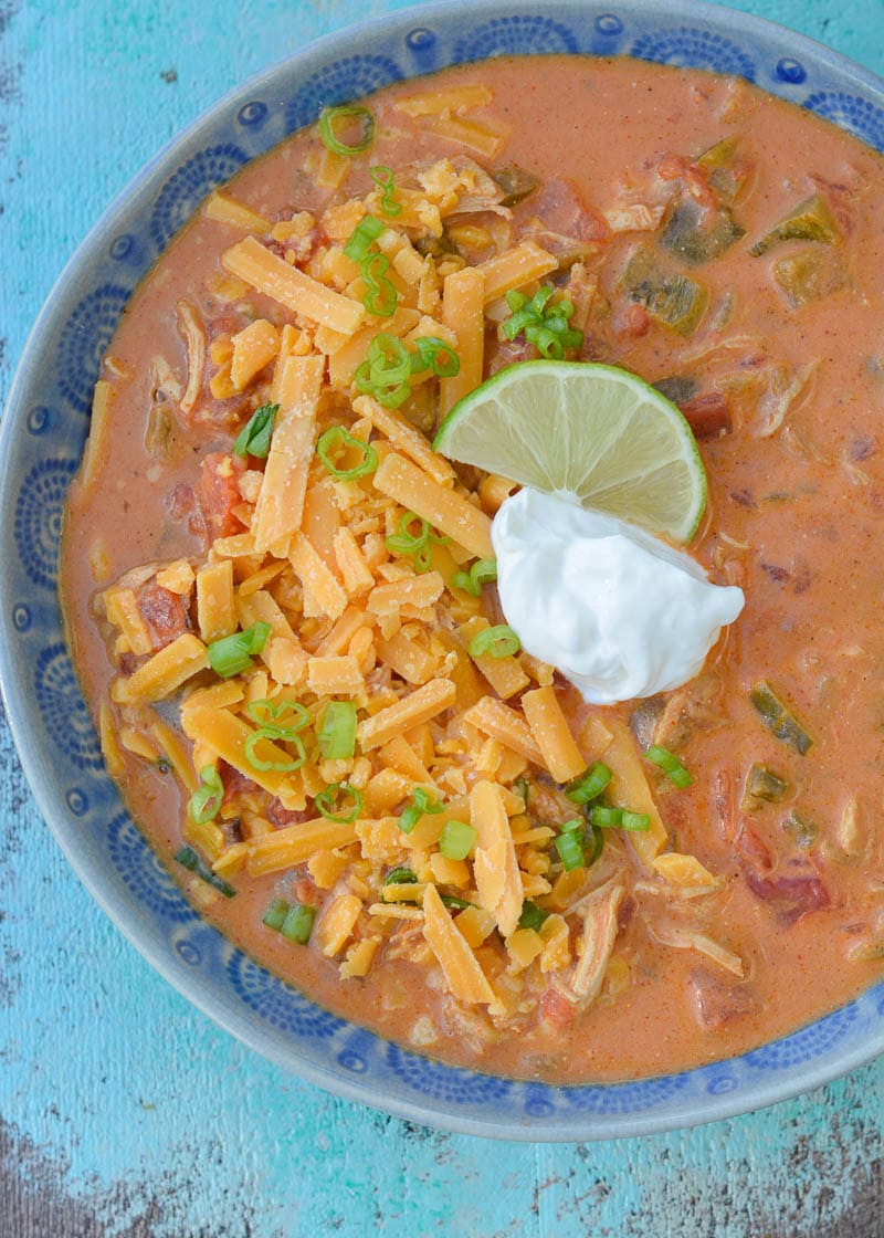overhead image of cheesy chicken enchilada soup in a blue bowl