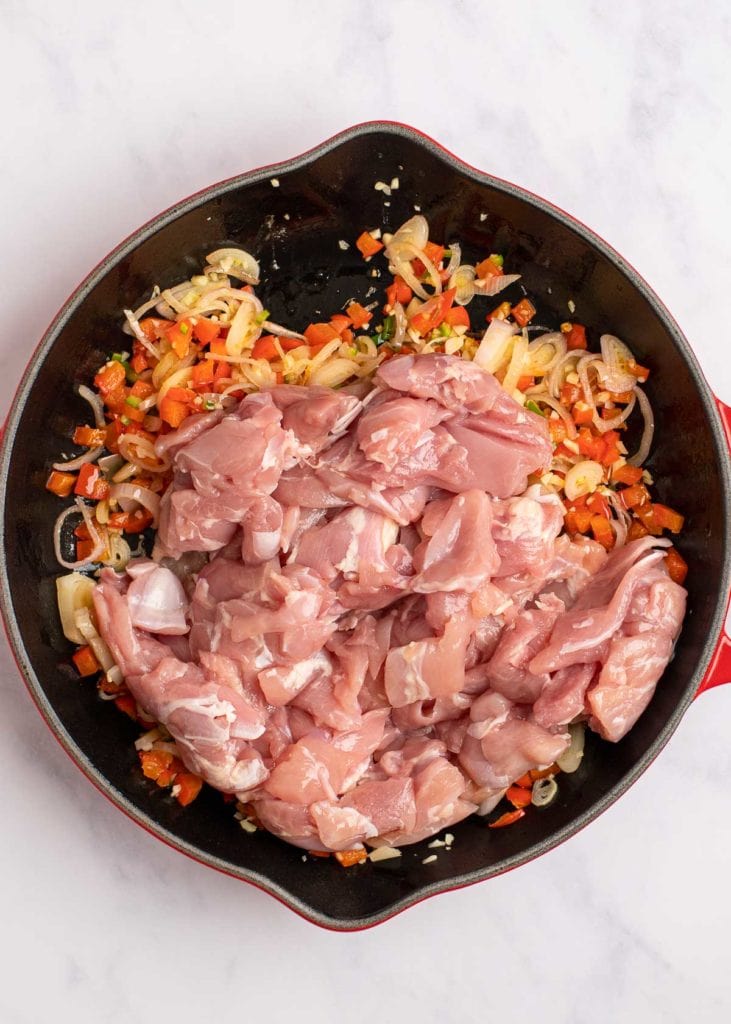 raw chicken added to saute veggies in a skillet for a one pan meal