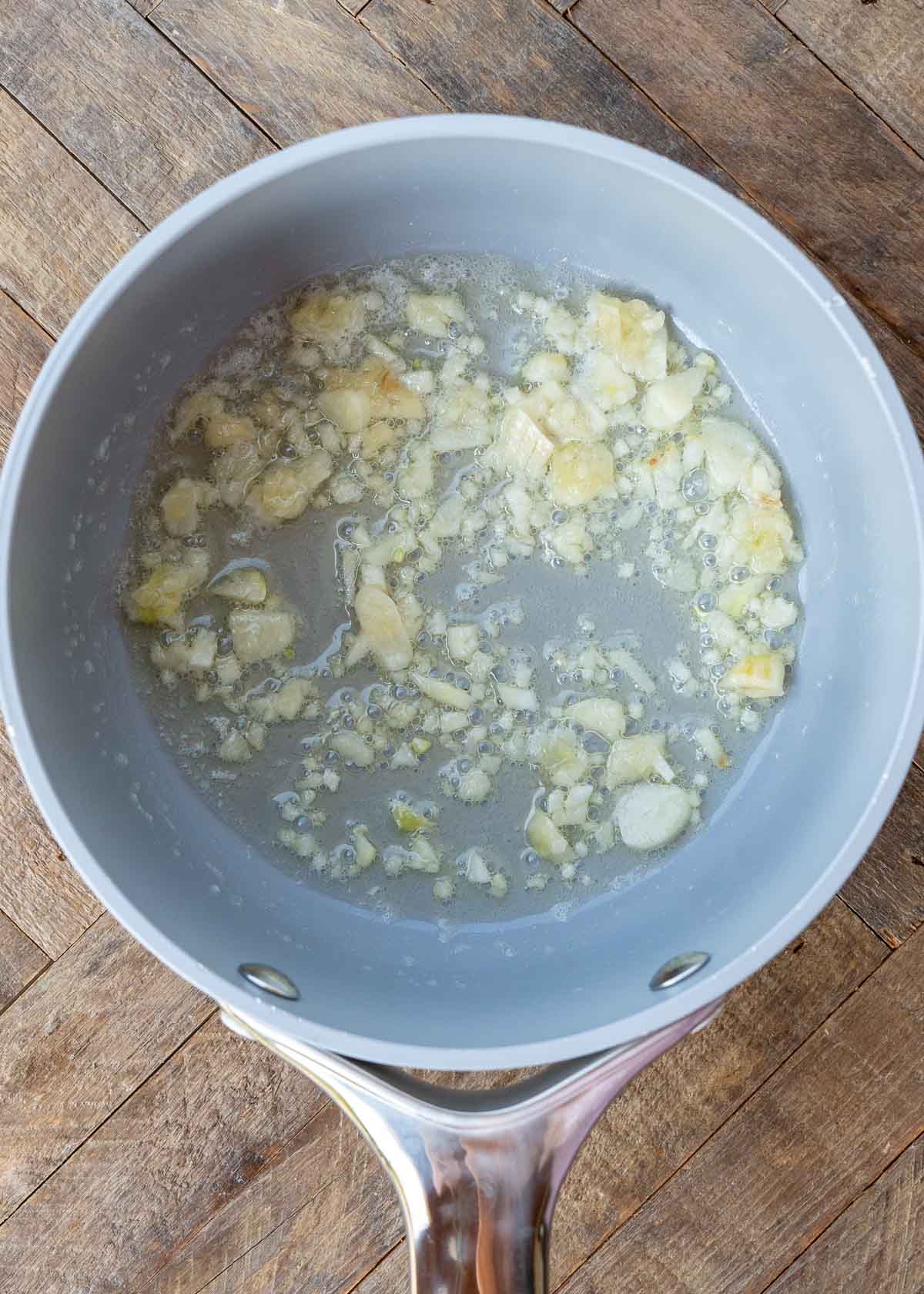 garlic being sautéed in gray sauce pan