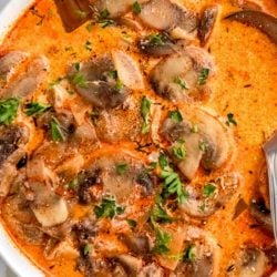 bowl of mushroom soup garnished with paprika and fresh herbs