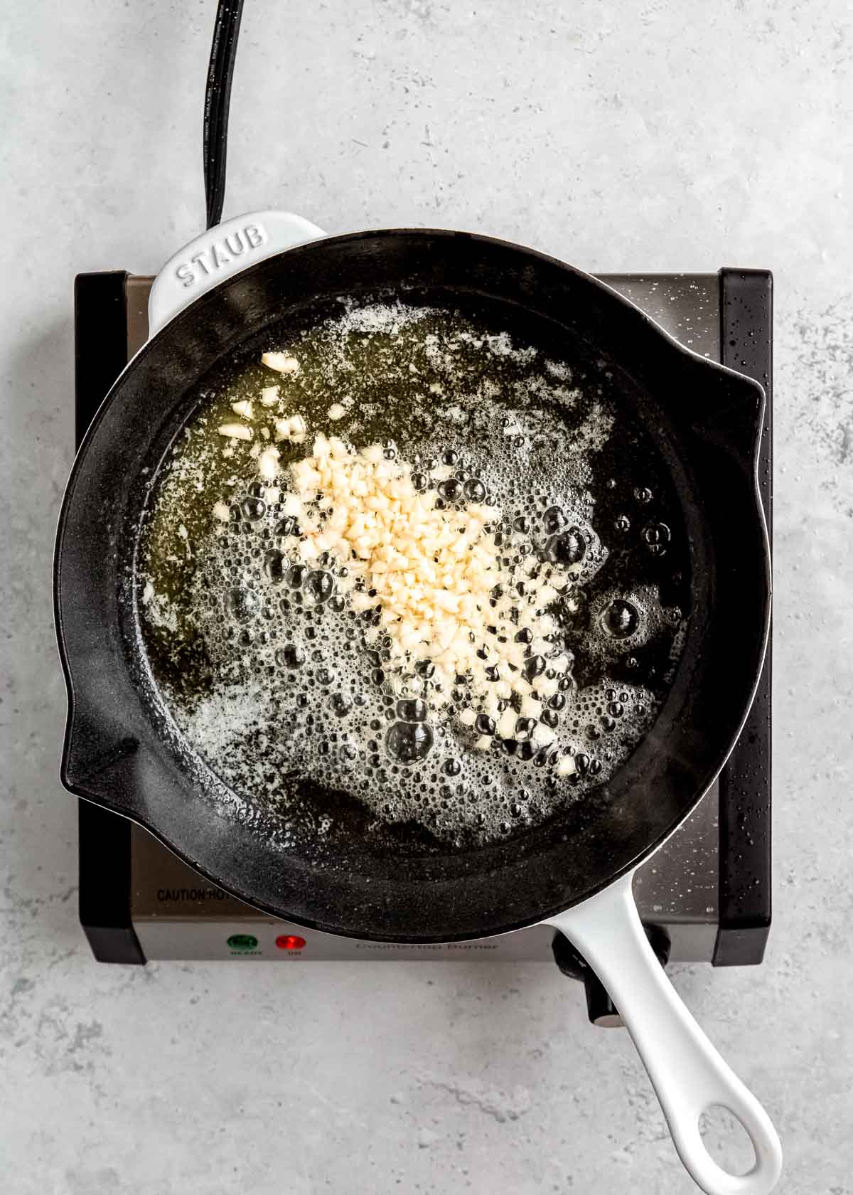 garlic being sauteed in cast iron skillet