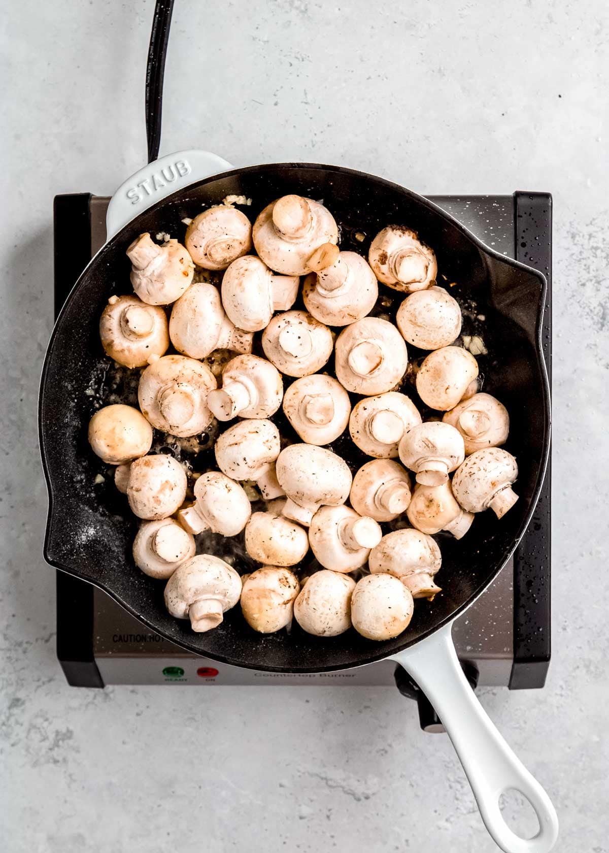 overhead shot of uncooked mushrooms in cast iron skillet
