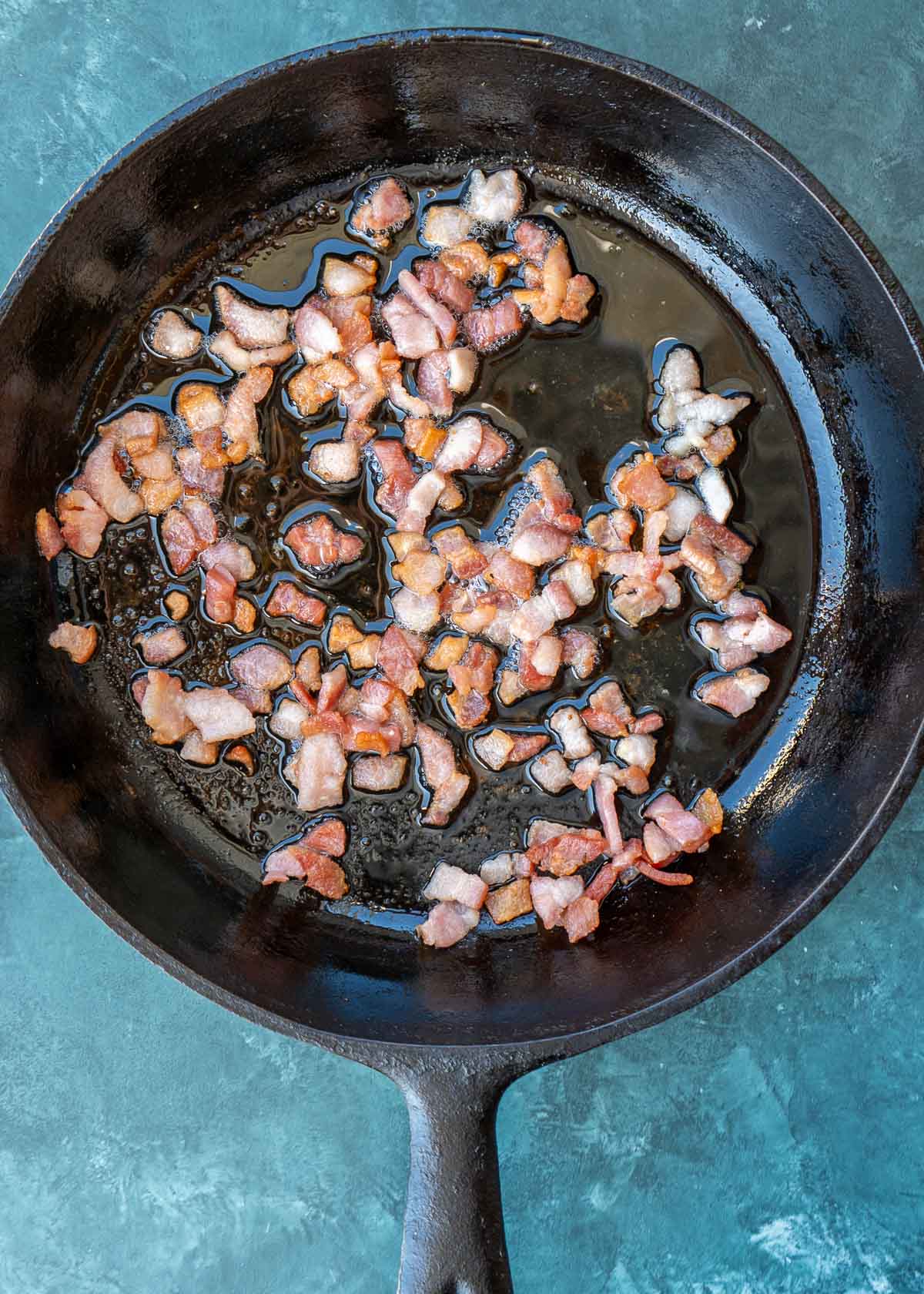 cooked bacon pieces in a cast iron skillet