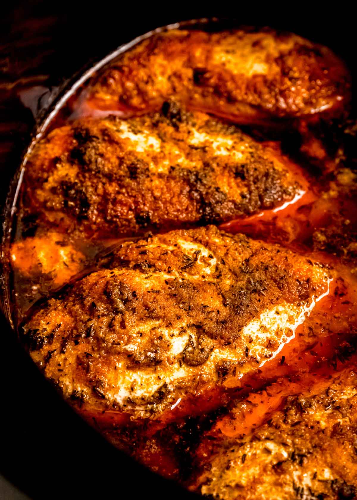 close up of cooked chicken breasts in black slow cooker