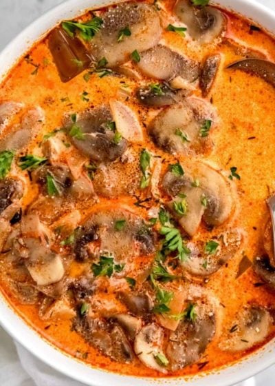 bowl of mushroom soup garnished with paprika and fresh herbs