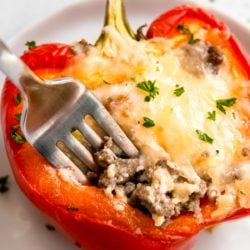 close up of breakfast stuffed bell pepper on white plate with fork
