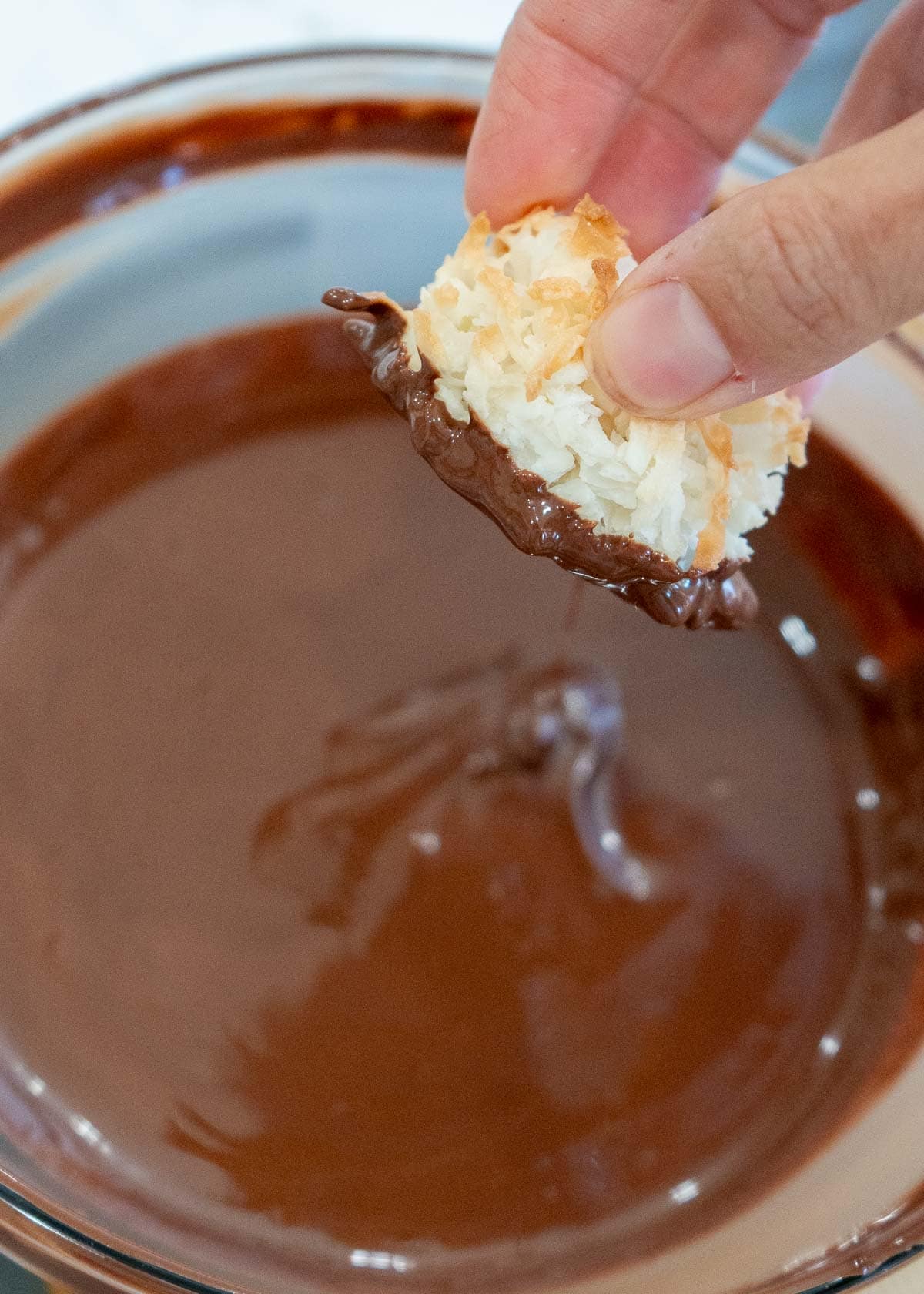 a coconut macaroon being dipped in chocolate