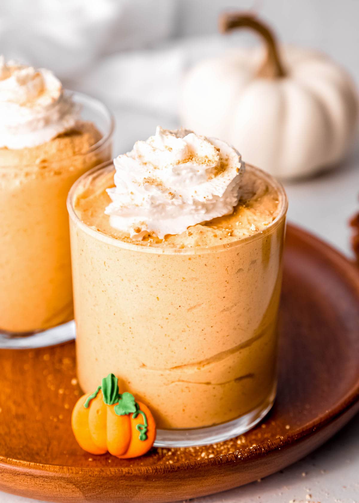 shot of two jars of pumpkin mousse, topped with whipped cream and cinnamon