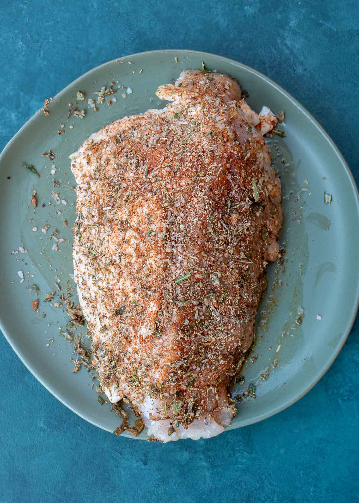 a turkey breast on a plate with a herb rub