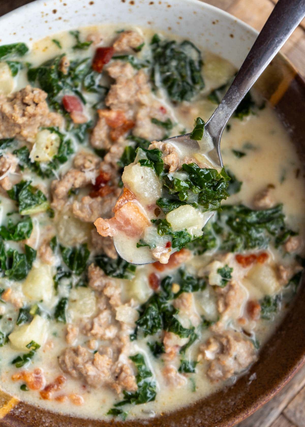 a bowl off sausage and kale soup with a spoon