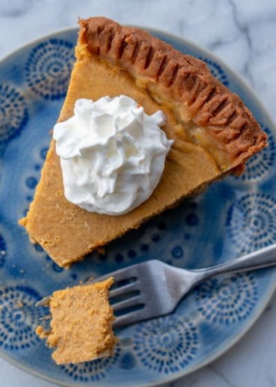 an overhead shot of a slice of keto pumpkin pie with whipped cream