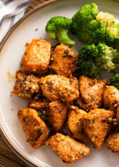 close up shot of garlic butter chicken bites and broccoli on a white plate