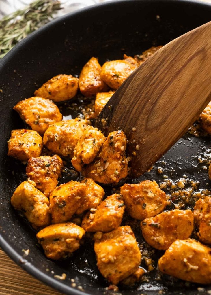 garlic butter chicken bites being turned in a cast iron skillet