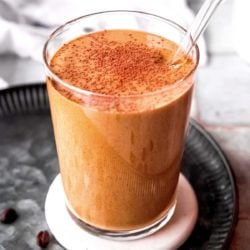 keto smoothie in a clear glass, dusted with cocoa powder
