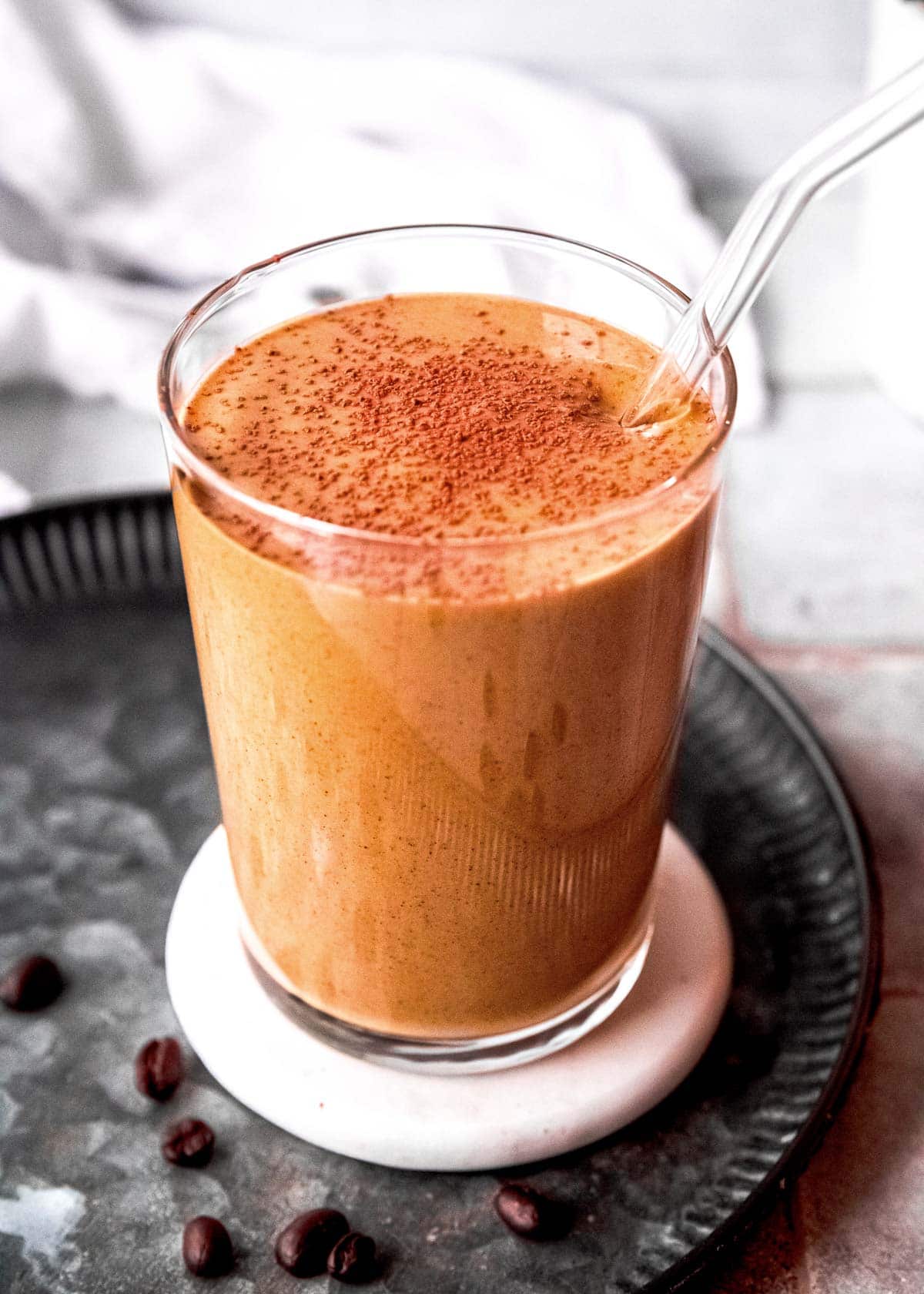 keto smoothie in a clear glass, dusted with cocoa powder