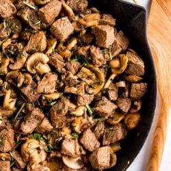 steak and mushrooms skillet garnished with fresh herbs