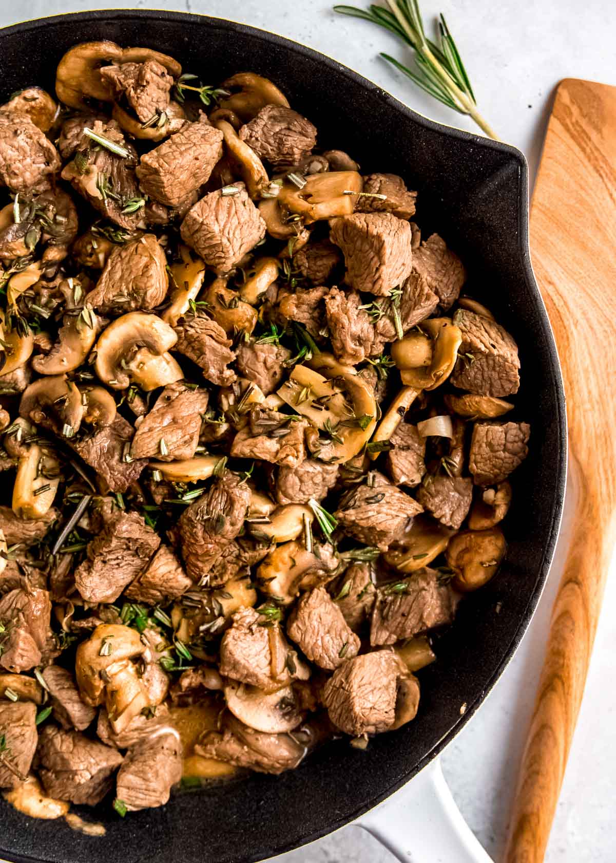 steak and mushrooms skillet garnished with fresh herbs