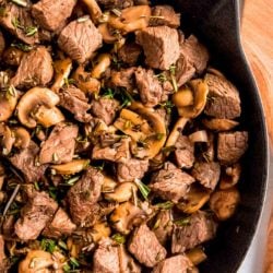 cast iron skillet with steak and mushrooms in a garlic butter sauce