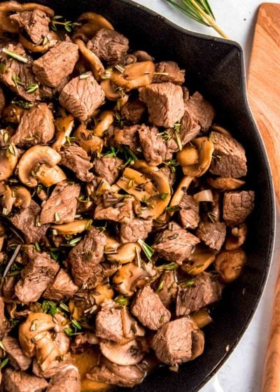 cast iron skillet with steak and mushrooms in a garlic butter sauce