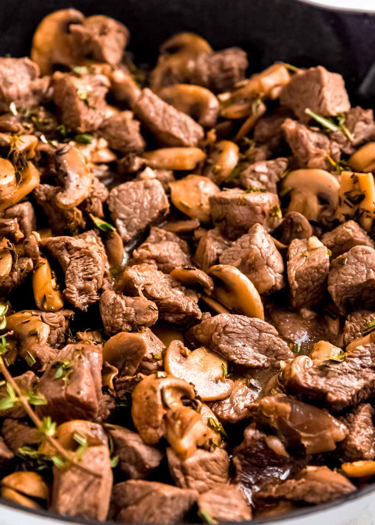 a full skillet of steak and mushrooms with garlic butter sauce