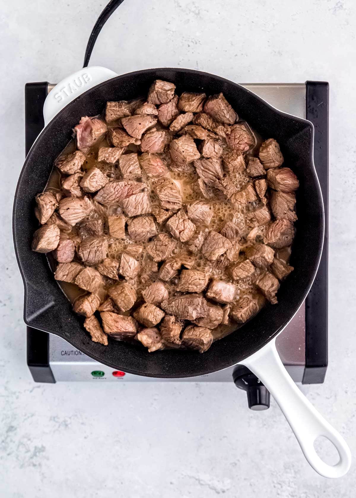 browned steak cubes in a skillet