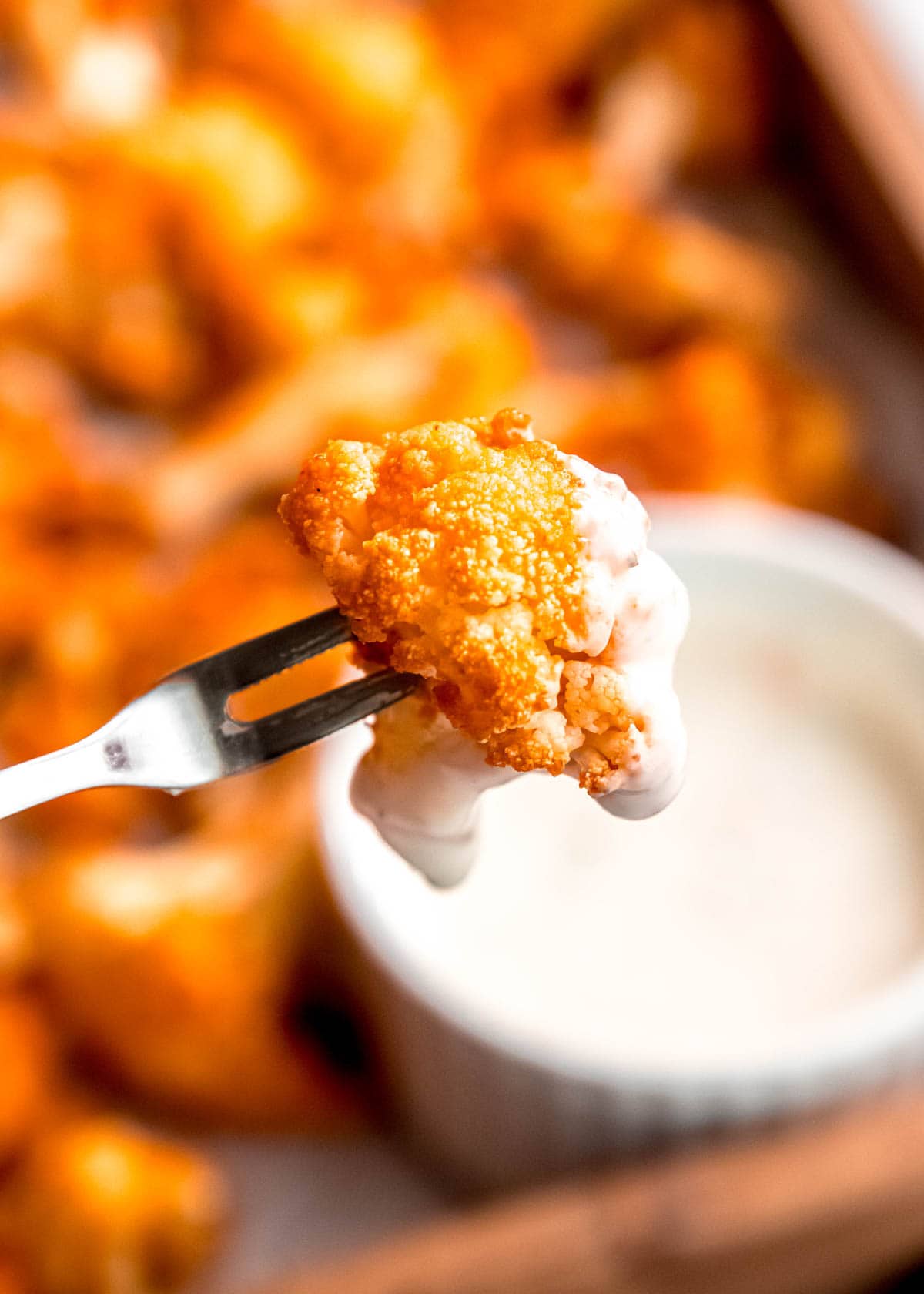 close up image of piece of cauliflower being dipped in dipping sauce